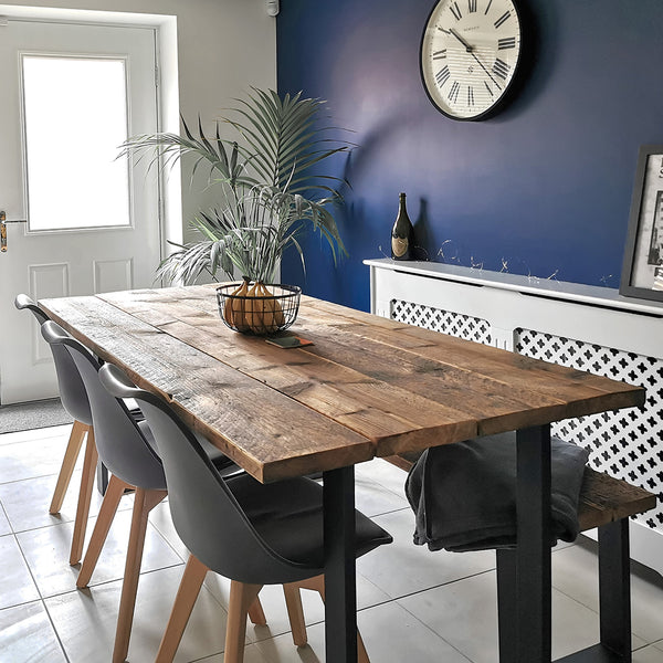 Industrial reclaimed timber scaffold board dining table with bench and square frame base in a home with 3 chairs
